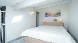 A bedroom with a bed, a painting, two wall-mounted lamps, and a wooden headboard. - Bright duplex apartment - sleeps 5 (Valras-Plage)
