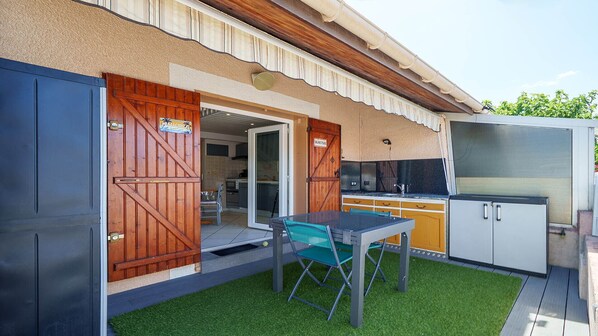 A patio with a table and chairs, a grill, and a sliding door leading to a kitchen. - Bright duplex apartment - sleeps 5 (Valras-Plage)