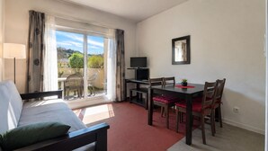Une chambre d’hôtel avec un lit, une table à manger avec des chaises, une télévision et un balcon avec vue.
