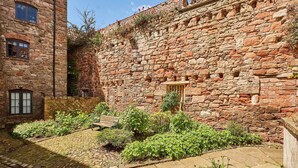 Un edificio de piedra con un patio, un banco y una puerta de madera.