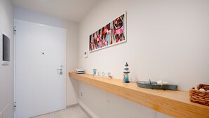 A reception area with a wooden counter, a 'Welcome' sign, a painting, and a door.