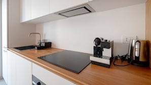 A modern kitchen with a black countertop, a coffee machine, and a kettle.