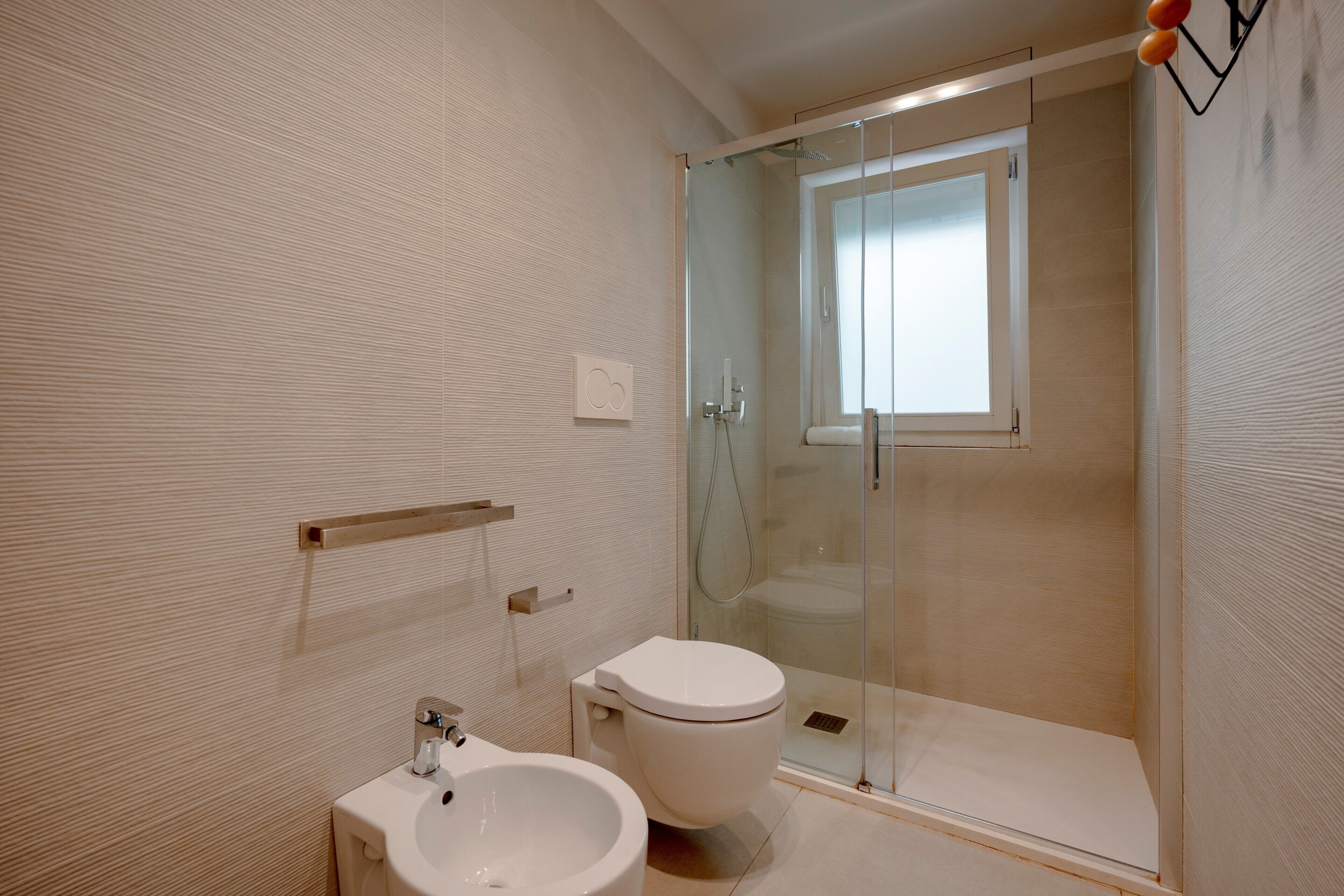 Une salle de bain moderne dotée d’une douche à parois de verre, de toilettes et d’un bidet.