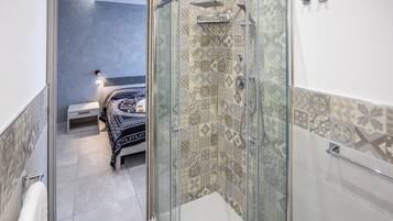 A bathroom with a shower, a bed, and a small bedside table.