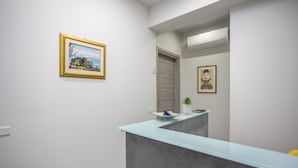 A reception area with a glass counter, framed artwork on the wall, and a door leading to another room. - Alla Corte degli Dei (Tropea)