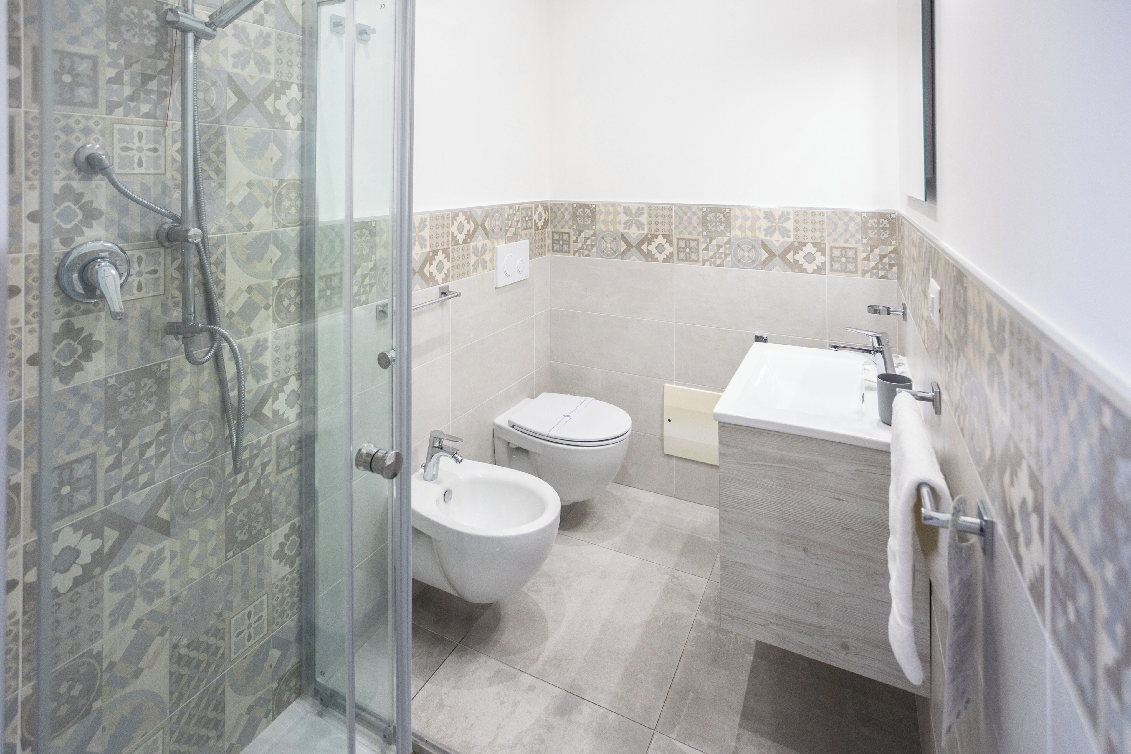 A bathroom with a shower, bidet, toilet, and sink.