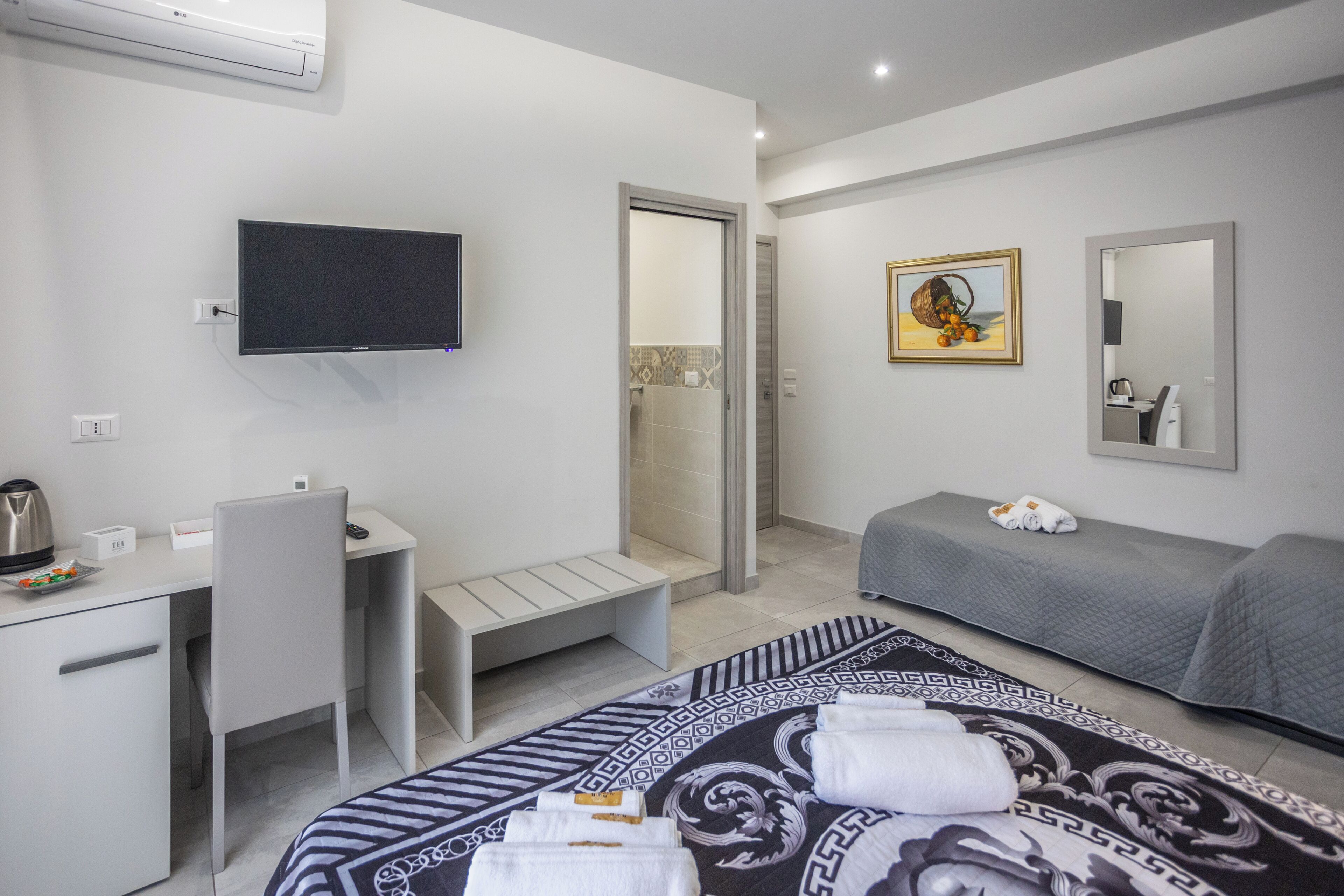 Une chambre d’hôtel équipée d’un lit, d’un bureau, d’une chaise, d’une télévision, d’une douche et d’un tableau.