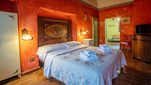 Une chambre d’hôtel avec un lit, une télévision, une armoire en bois et une salle de bain visible à travers une porte ouverte.