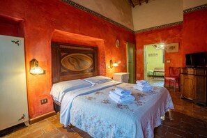 A hotel room with a bed, a television, a wooden cabinet, and a bathroom visible through an open door. - Toskana Holiday Home With Pool (Siena)
