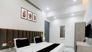 Een moderne hotelkamer met een groot bed, nachtkastjes, een flatscreen televisie en lijstwerken aan de muur.
