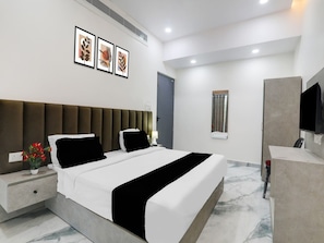 A modern hotel room with a large bed, bedside tables, a flat-screen TV, and framed artwork on the wall. - Super Collection O Quila Road (Lucknow)