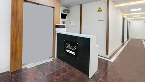 Een receptiegedeelte met een receptiebalie, een brandblusser, een waarschuwingsbord en een receptieschild.