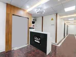 A reception area with a reception desk, a fire extinguisher, a caution sign, and a reception sign. - Super Collection O Quila Road (Lucknow)