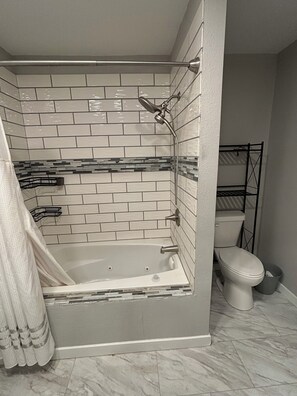 A bathroom with a bathtub, toilet, and shower.