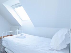 A single white bed in a room with a sloped ceiling and a skylight. - House in Saint-pabu Near Stunning Beaches (Saint-Pabu)