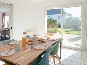 A dining area with a wooden table, chairs, and a view of the outside. - House in Saint-pabu Near Stunning Beaches (Saint-Pabu)