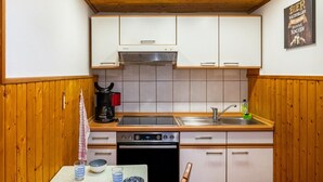 Eine kleine Küche mit Holzausstattung, einem Backofen, einer Kaffeemaschine und einem Spülbecken.