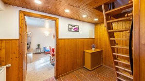 Ein Holzinnenraum mit einer Rezeption, einer Holztreppe und einer Tür zu einem weiteren Raum.