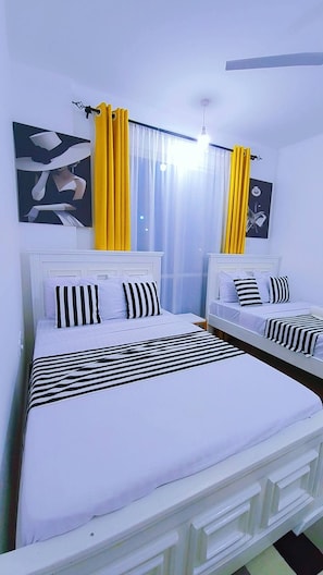 A bedroom with two beds, each with white headboards and black and white striped bedding. - Modern Coastal Apartment - Lift/Elevator Access,7 mins from beach, 24hr security (Mombasa)