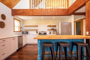 A modern kitchen with a wooden island, bar stools, and a view of the upper floor. - Blue Island retreat- Secluded, Quiet and Welcoming (Fort Augustus)