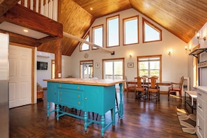 A spacious kitchen with a wooden ceiling, a turquoise island with drawers, and a dining area with wooden chairs. - Blue Island retreat- Secluded, Quiet and Welcoming (Fort Augustus)