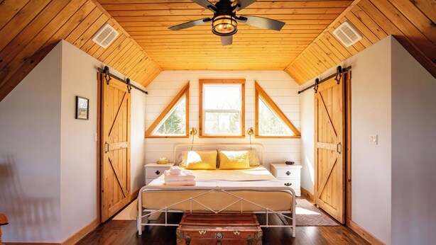 Quarto com cama, cómoda, janela e ventoinha no teto.