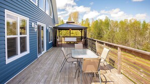 Um terraço com mesa, cadeiras, um gazebo e guarda-corpo.