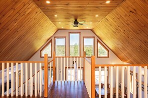 A wooden interior with a sloped ceiling, a ceiling fan, and three windows. - Blue Island retreat- Secluded, Quiet and Welcoming (Fort Augustus)