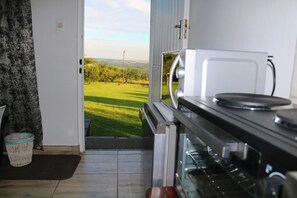 Eine Küche mit Blick auf ein grünes Feld, einem weißen Backofen und einer schwarzen Kochplatte.