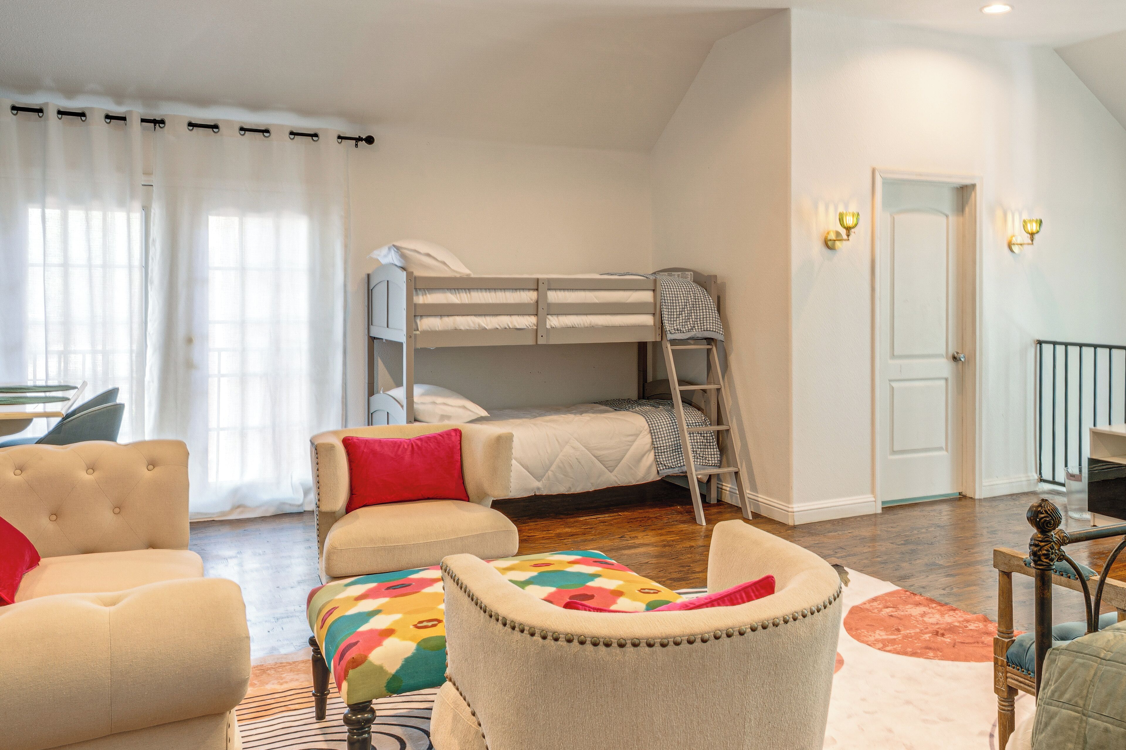 Um quarto com beliche, sofá, tapete colorido e escrivaninha.