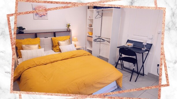 A bedroom with a bed, a desk, a chair, and a wardrobe.