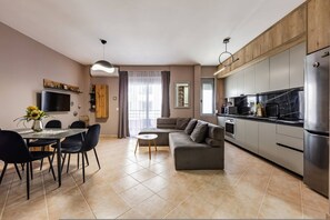 Eine moderne Küche mit Einbauofen, ein Essbereich mit Tisch und Stühlen sowie eine Wohnbereich mit einer Couch.