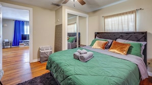 A bedroom with a bed, a ceiling fan, a wardrobe, and a bathroom visible through an open door.