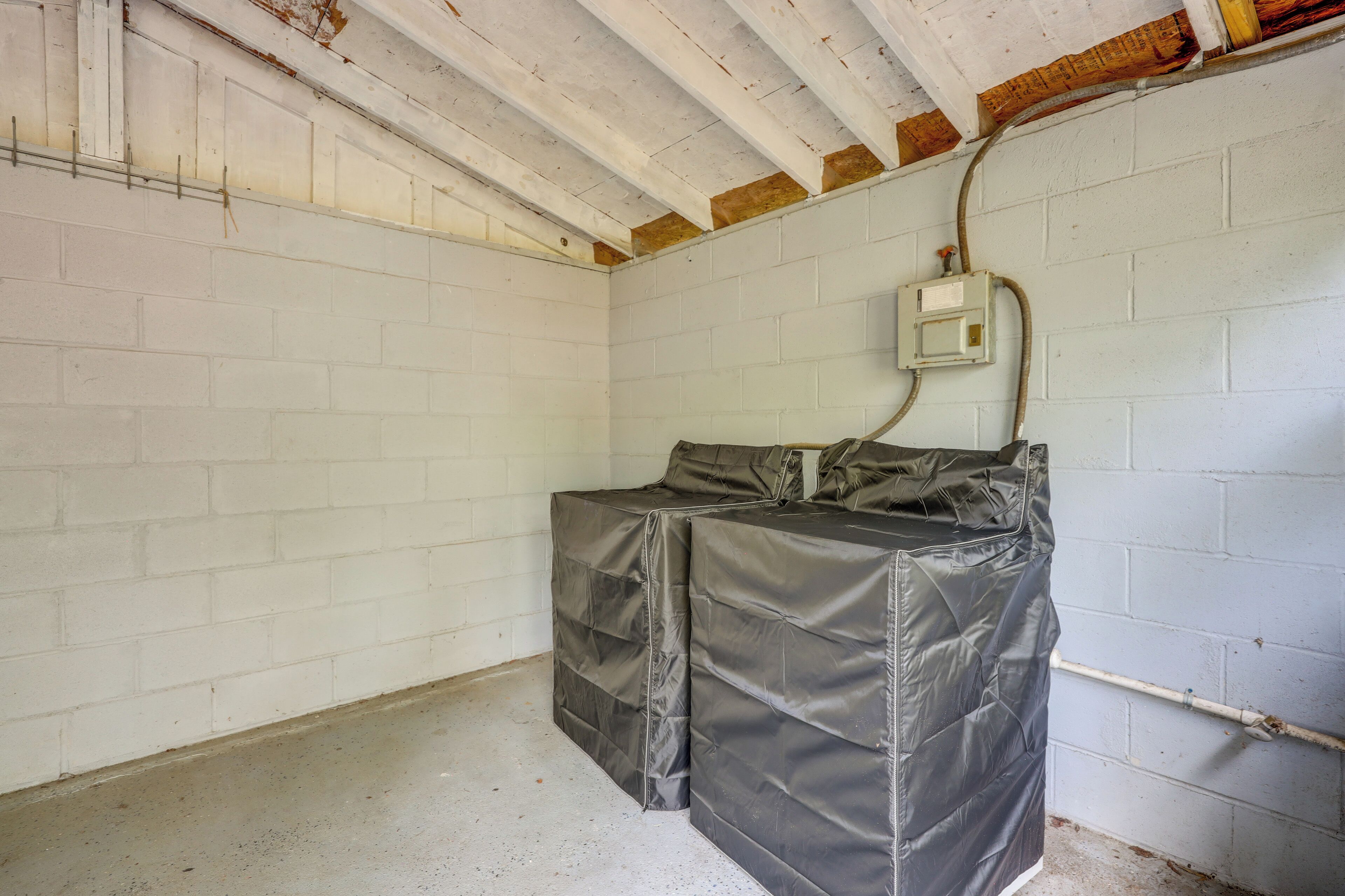 A room with white brick walls, a concrete floor, and a ceiling with exposed wooden beams.