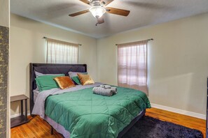 A bedroom with a bed, a ceiling fan, and a window with curtains.