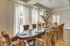 Ein Esszimmer mit einem langen Tisch, gemusterten Stühlen und einer Ziervase.