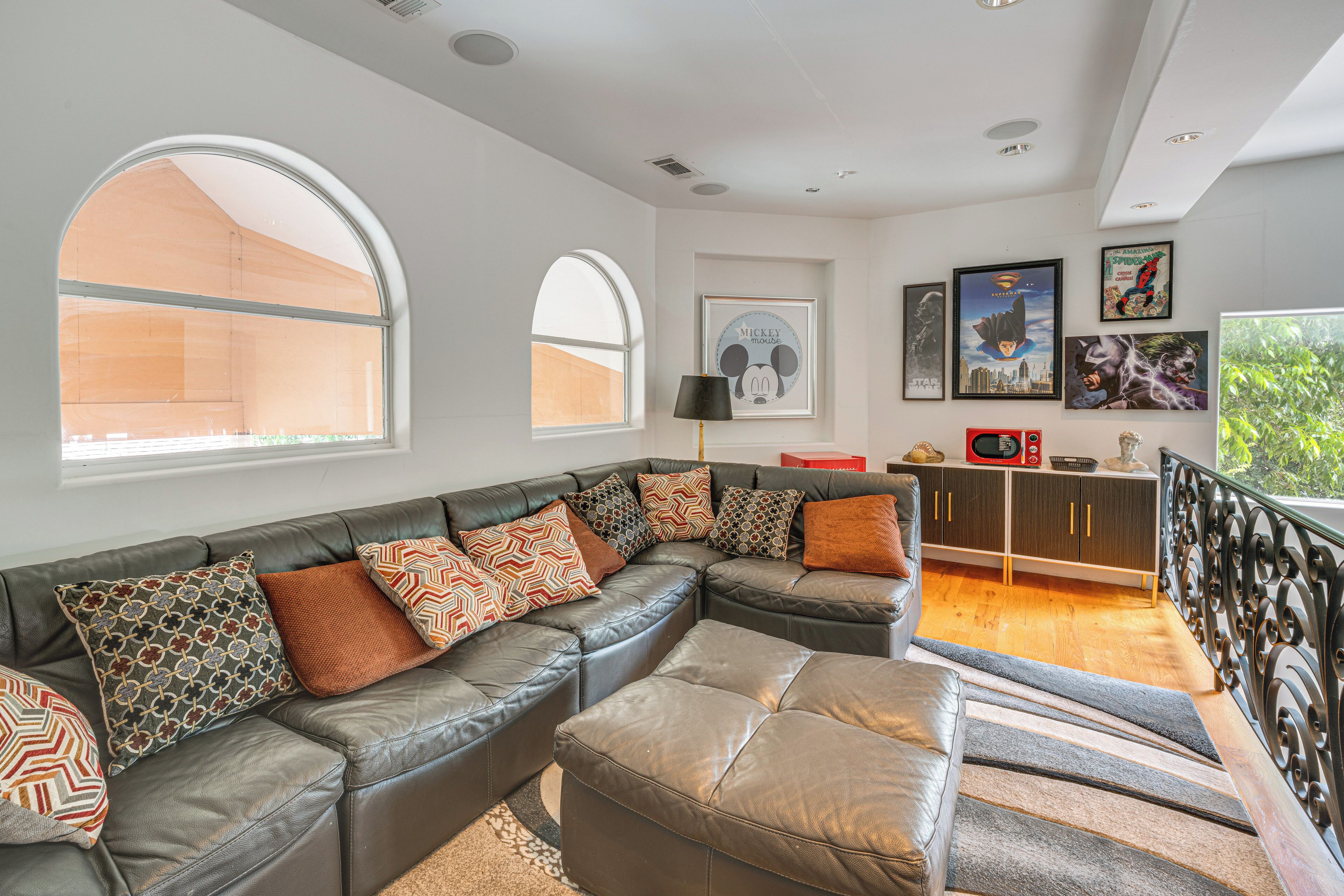 A modern living room with a sectional sofa, large windows, and a staircase leading to an upper level.