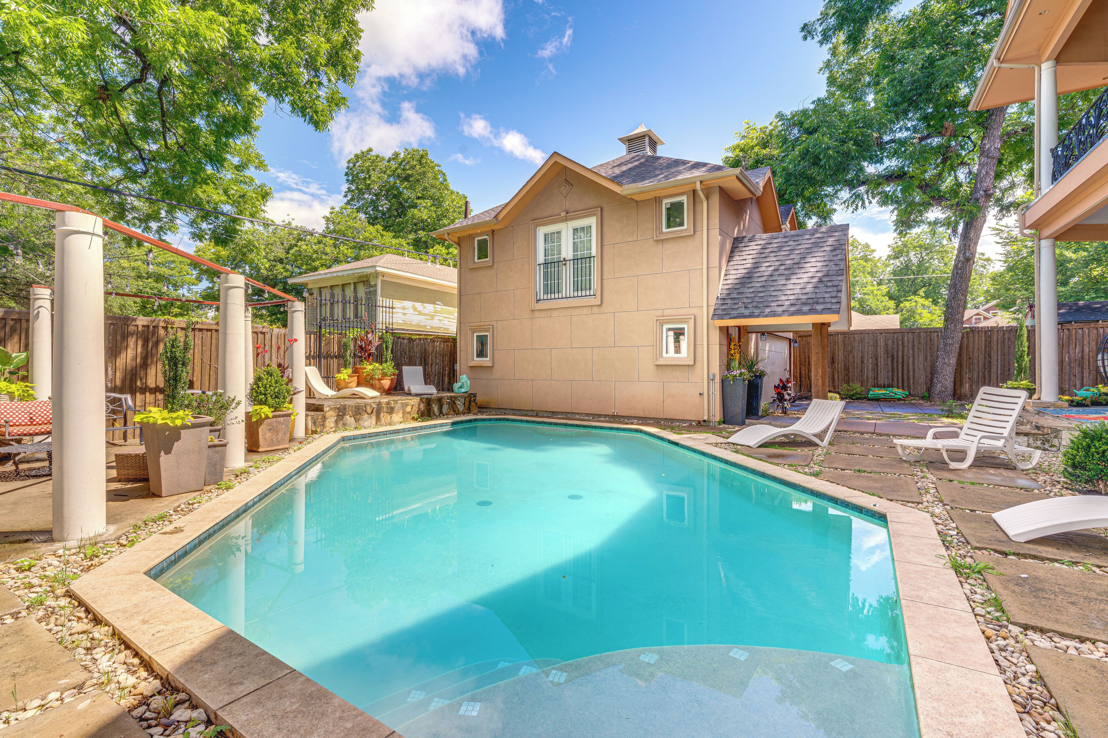 Un patio trasero con piscina, una casa y mobiliario exterior.