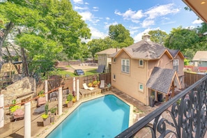 A backyard with a swimming pool, a covered patio, and a house with a sloped roof.