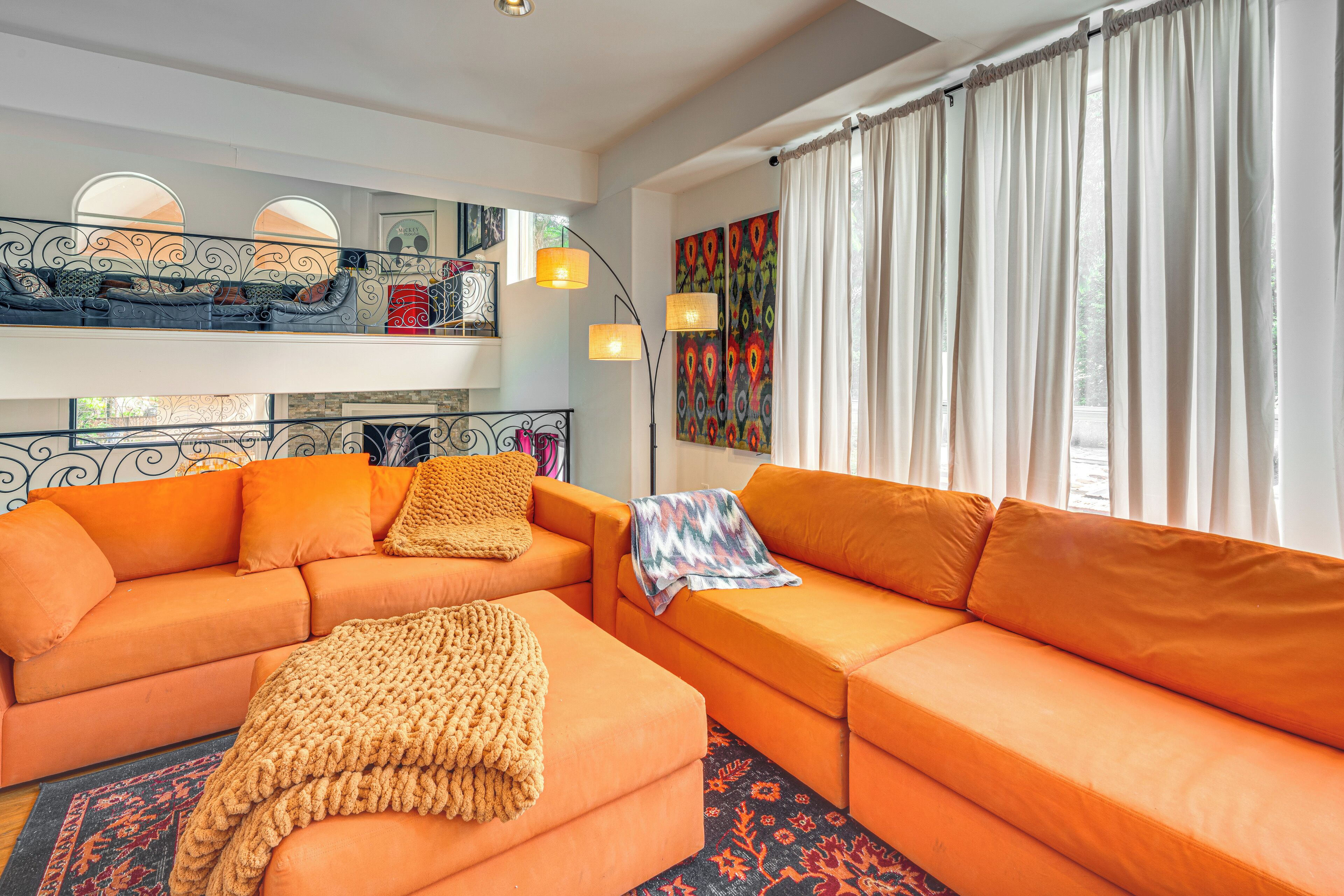 A living room with a sectional sofa, a small ottoman, and a patterned rug.