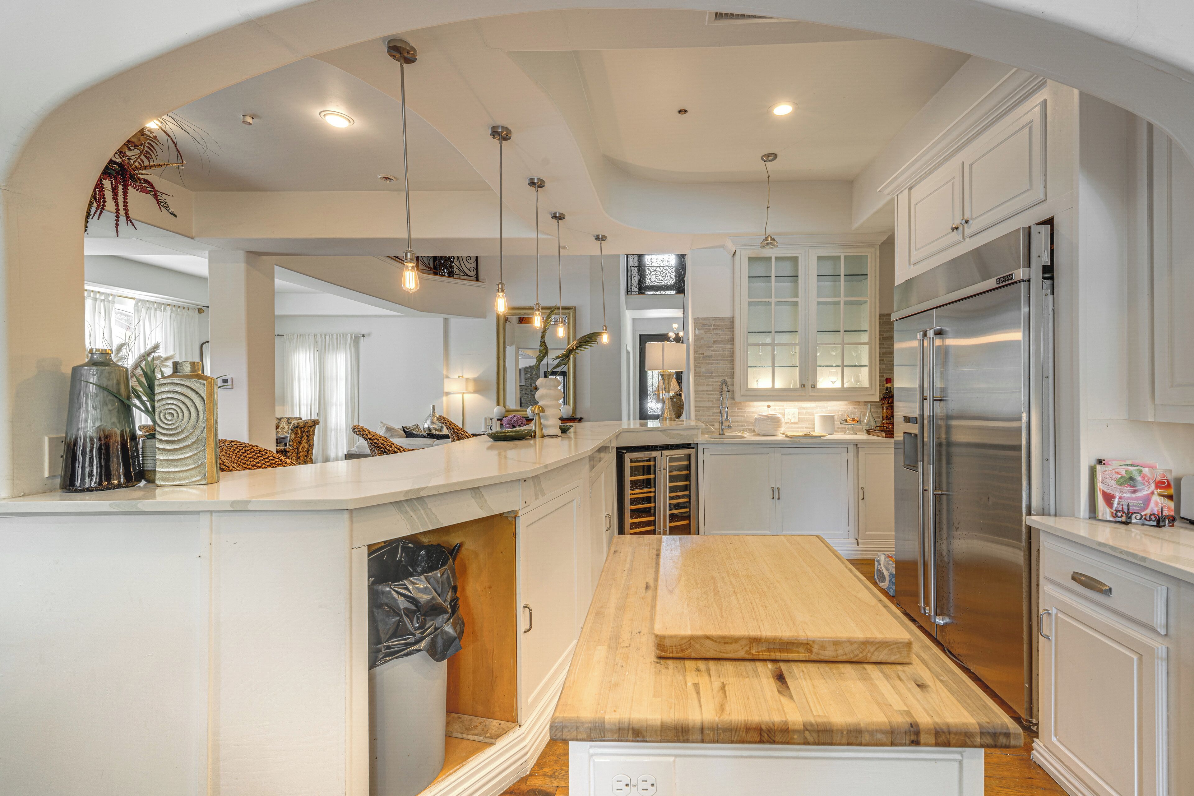 A modern kitchen with a central island, stainless steel appliances, and pendant lighting.