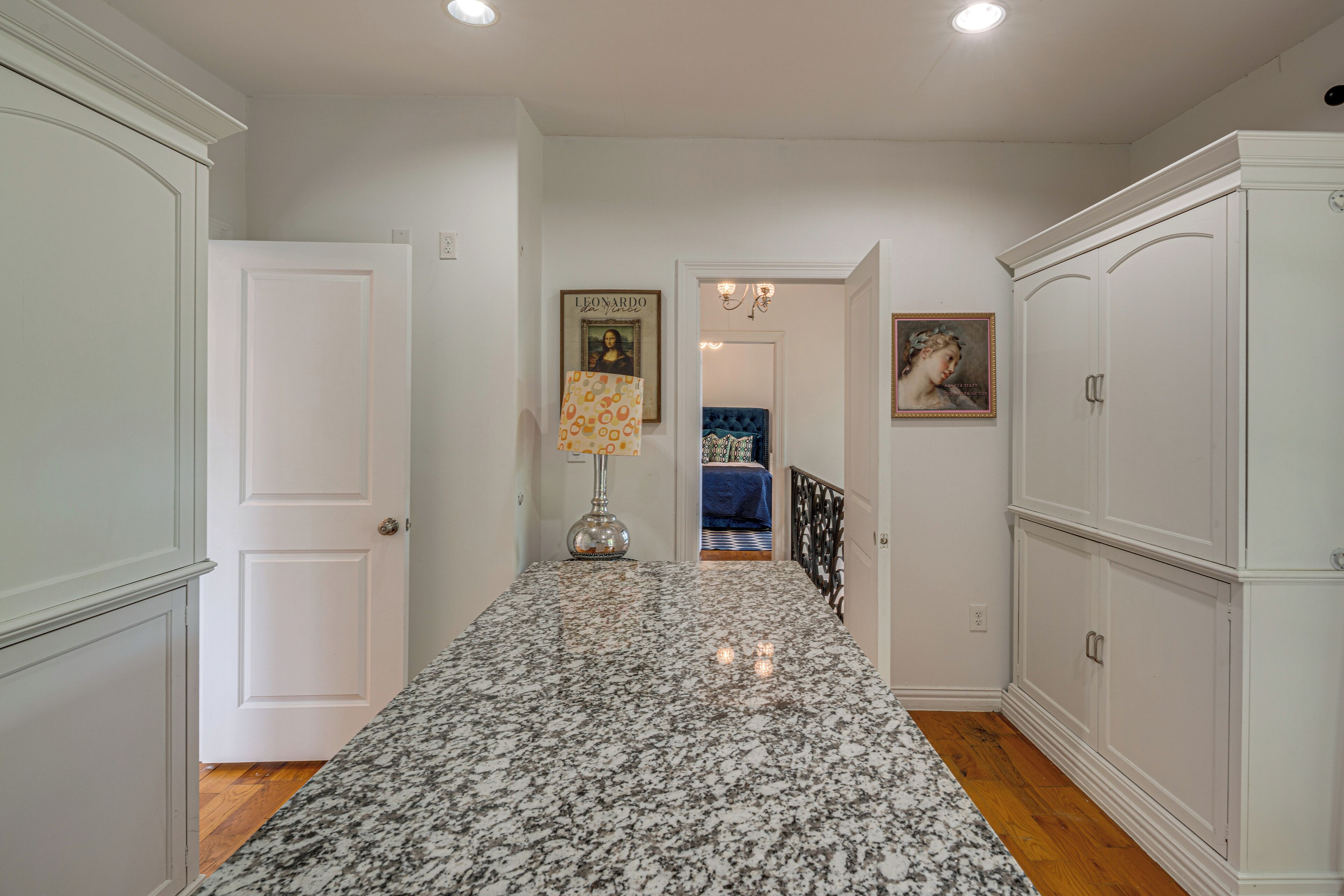 A hallway with a marble floor, white walls, and a door leading to a bedroom.
