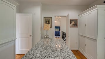A hallway with a marble floor, white walls, and a door leading to a bedroom.