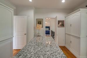 A hallway with a marble floor, white walls, and a door leading to a bedroom.