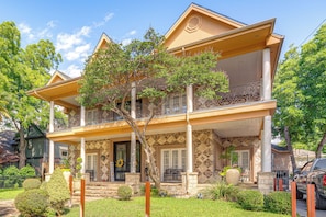 A two-story house with a balcony, a front porch, and a stone facade.