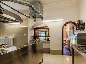 Une cuisine moderne dotée d’appareils électroménagers en acier inoxydable, d’un grand îlot central et offrant une vue sur une autre pièce à travers une porte en arc de cercle.