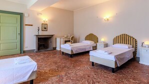 Habitació d'hotel amb dos llits individuals, escriptori, cadira, llar de foc i porta verda.