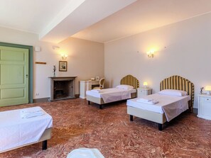 Ein Hotelzimmer mit zwei Einzelbetten, einem Schreibtisch, einem Stuhl, einem Kamin und einer grünen Tür.