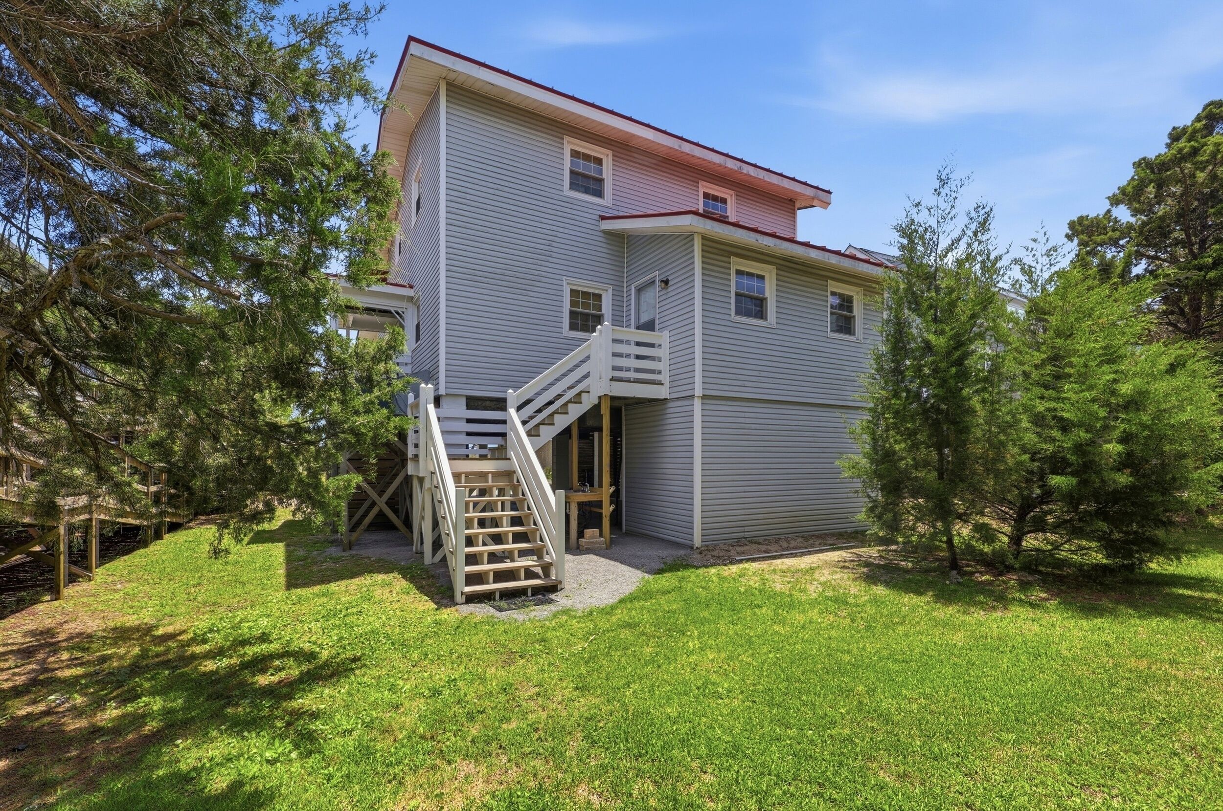 A two-story house with a front porch, a wooden staircase, and a small front yard.