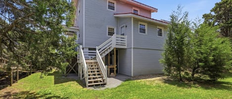 A two-story house with a front porch, a wooden staircase, and a small front yard.